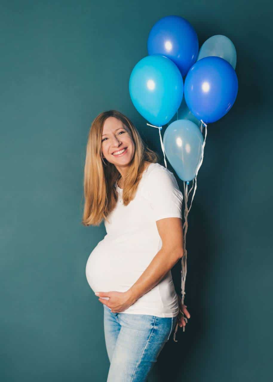 Schwangere Frau mit blauen Ballons, Babybauch-Fotografie.